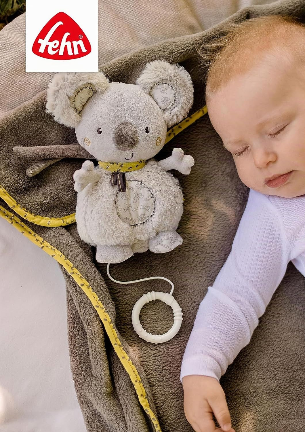 Koala FEHN zawieszona obok śpiącego dziecka w foteliku.