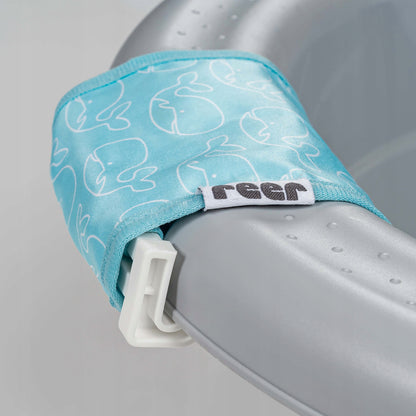 Zbliżenie białej klamry i niebieskiego brzegu siatki Reer MyHappyBath Sling 76072 ze wzorem wielorybów.