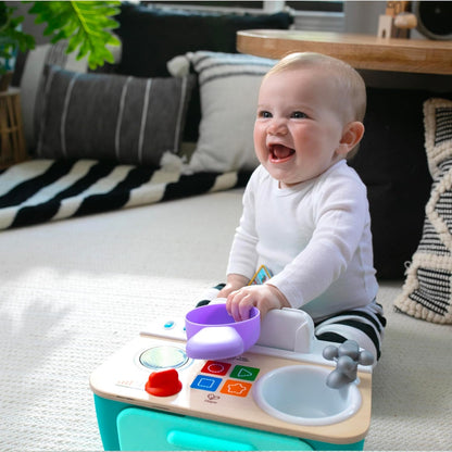 Dziecko uśmiechające się podczas zabawy kuchnią Baby Einstein Hape.