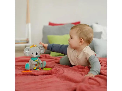 Dziecko leżące na czerwonym kocu sięga do zabawki FEHN DoBabyDoo Koala.
